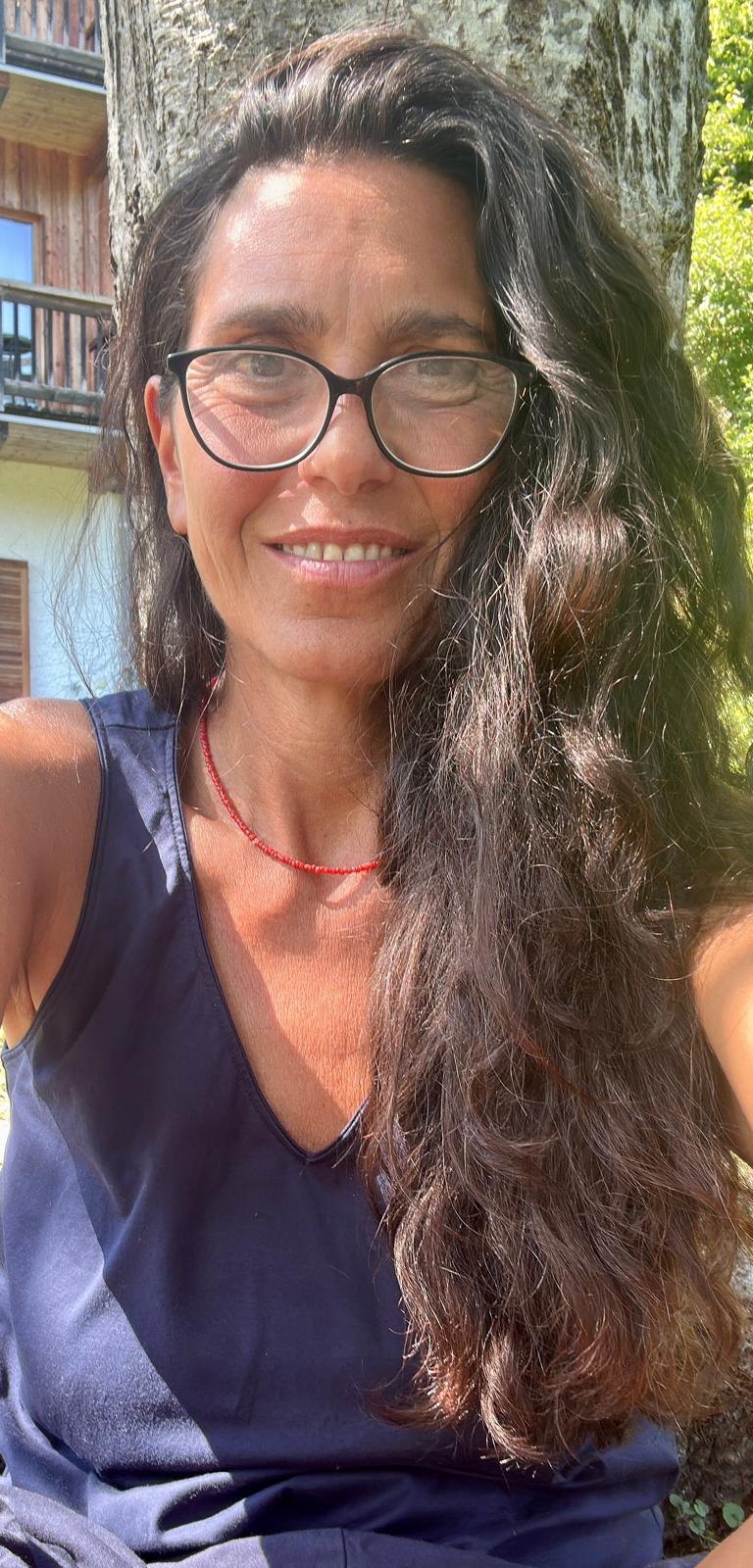 Ritratto di Dania Pirone sorridente all'aperto, con un albero alle spalle
